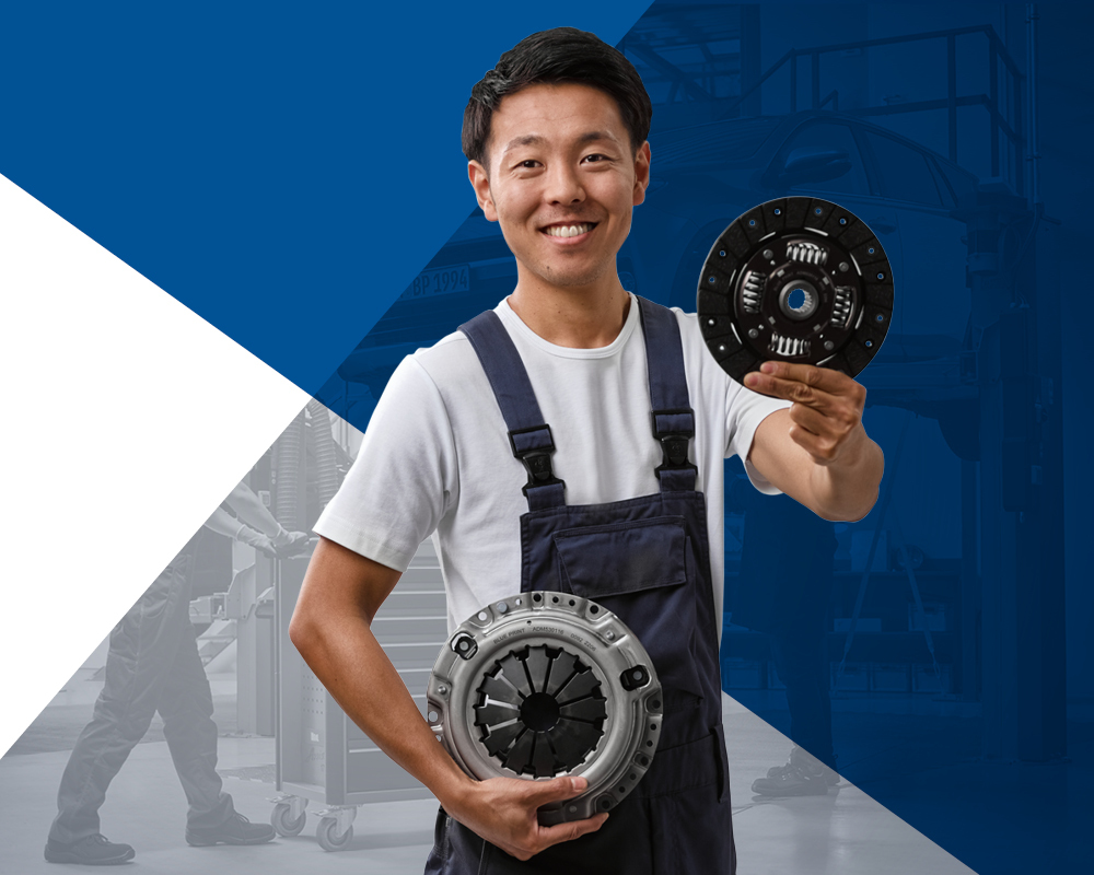 Автомеханік тримає у руках корзину зчеплення та натискний диск зчеплення