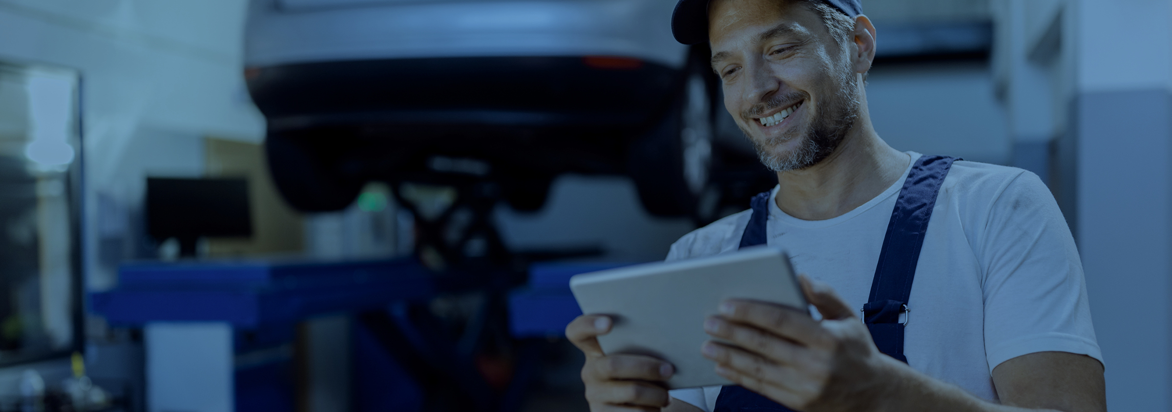 Задоволений автомеханік у автомайстерні підписується на інформаційну розсилку новин на своєму планшеті