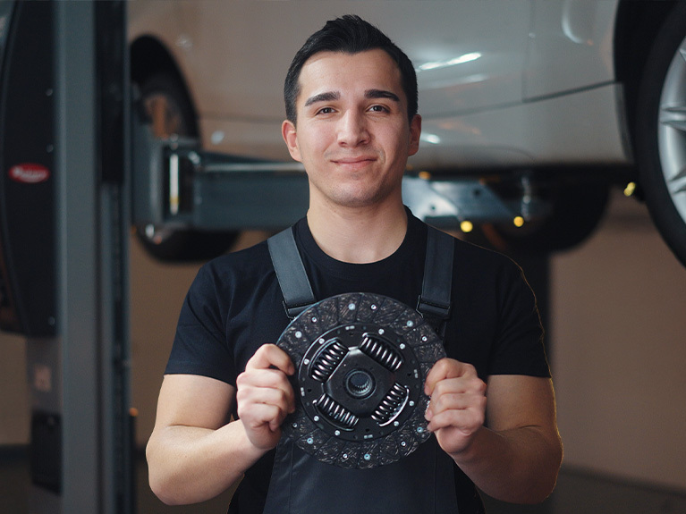 Два автомеханіка у автомайстерні нахилились над компонентами зчеплення